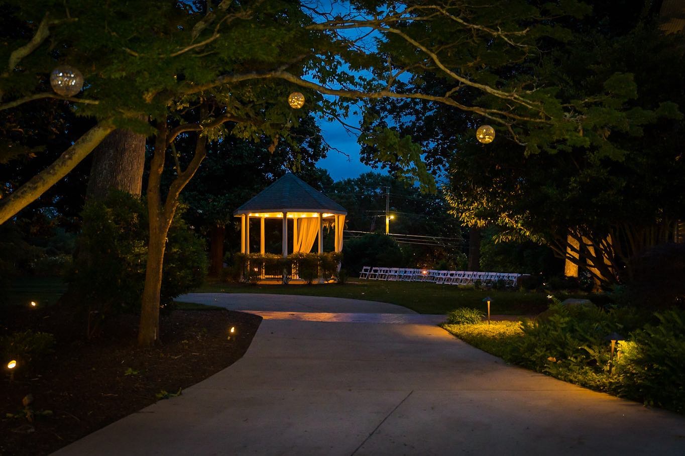 illuminated walkway leading to outdoor wedding ceremony at dusk
