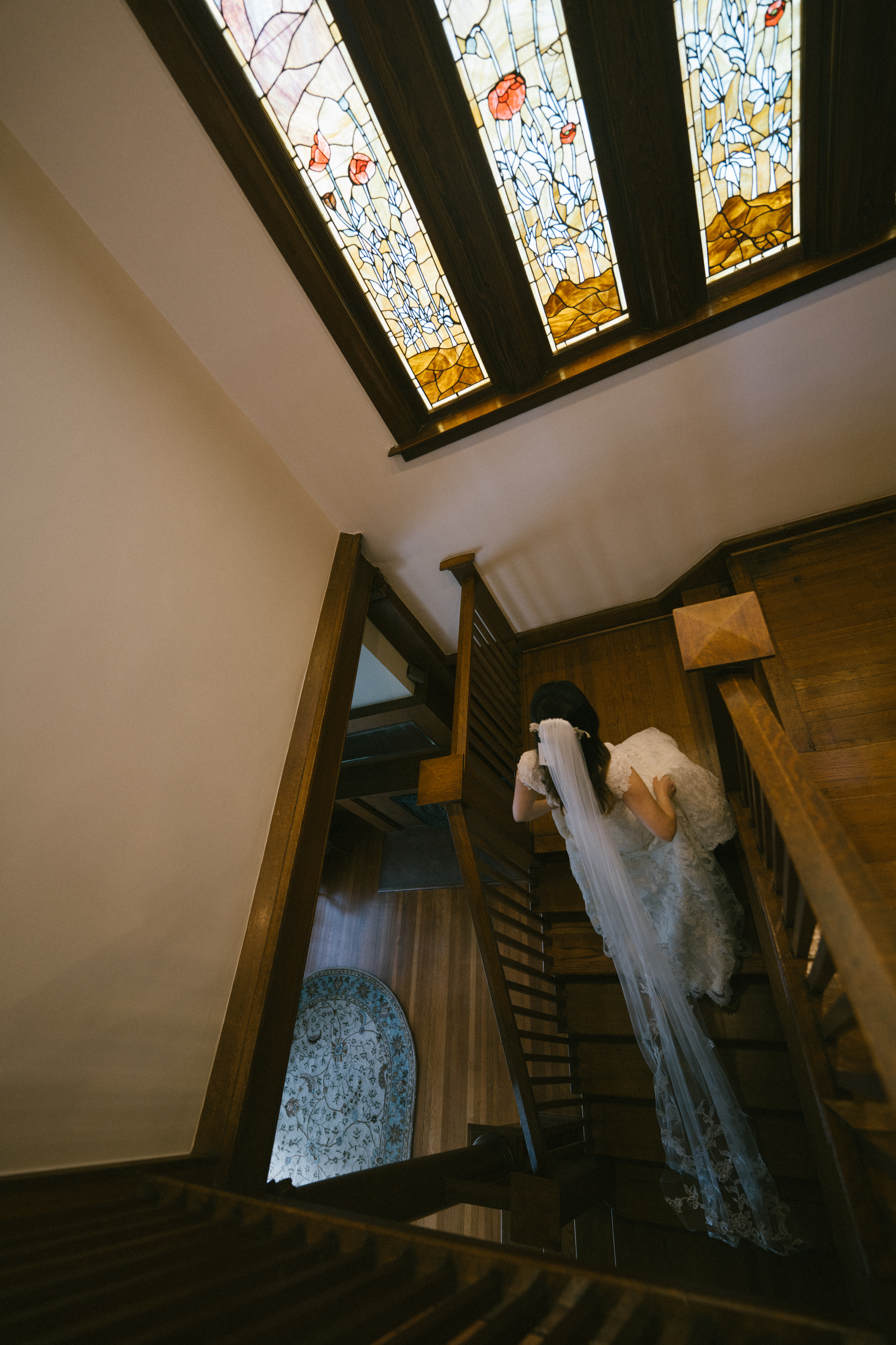 bride walking up stairs toward stained glass windows