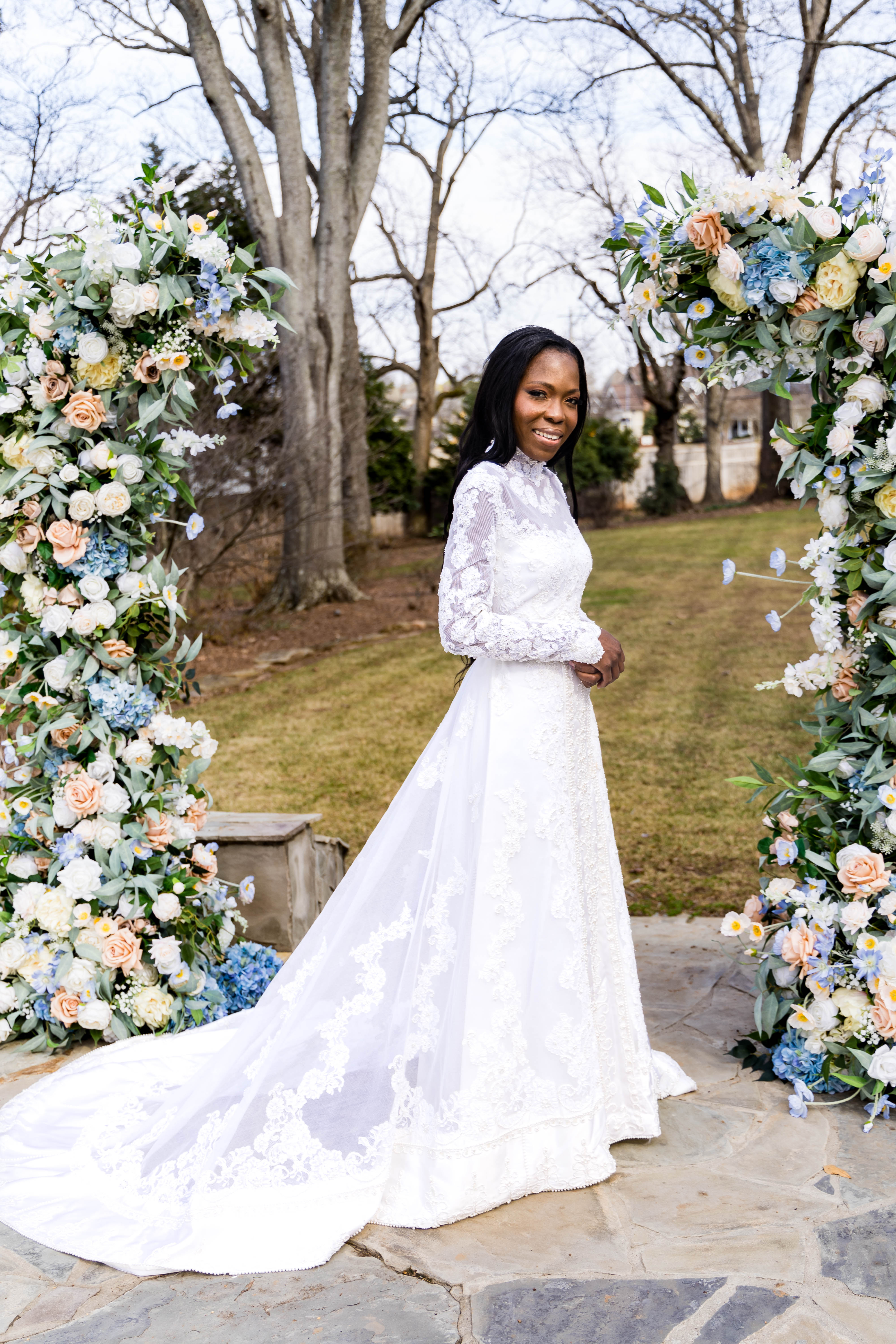 bride standing between floral columns outdoors