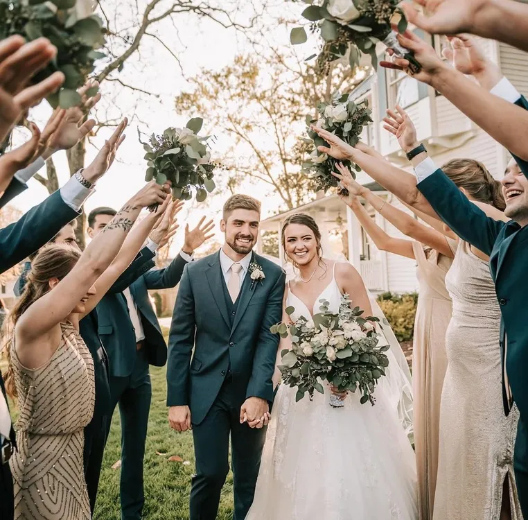 bride and groom walking through wedding party's arms